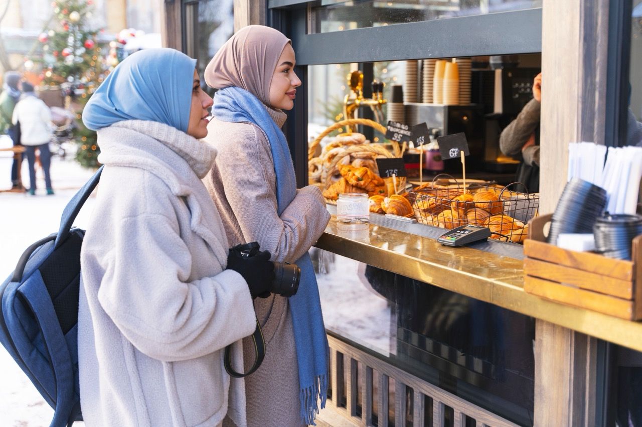 two_muslim_women_buying_food_from_pastry_shop_while_traveling_8bb5b1a5f3 Large.jpeg